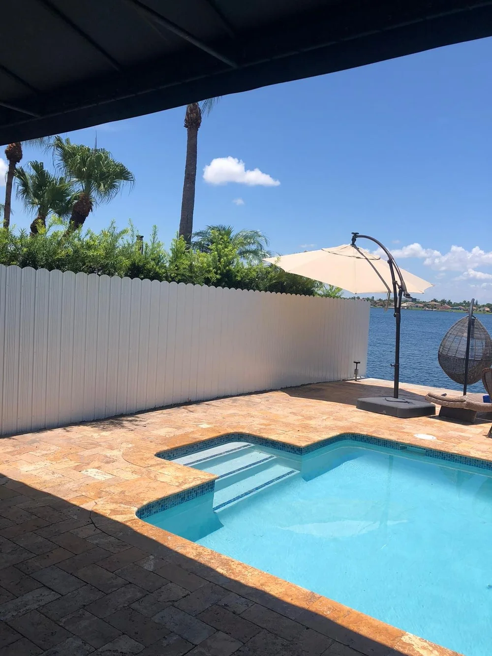 White privacy fence beside a waterfront swimming pool